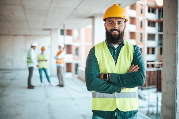 a construction lead smiles while team chats in the background on an unfinished building